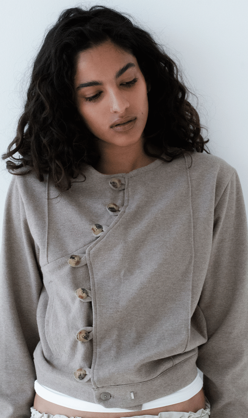 A model wearing a jacket in neutral colors and clean design inspired by the Japanese philosophy of Wabi Sabi