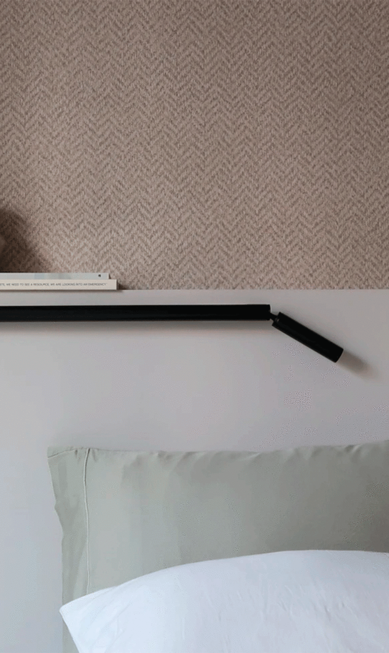 Slim, elongated lamp with a movable end that can be adjusted for easy reading when placed at the head of a bed