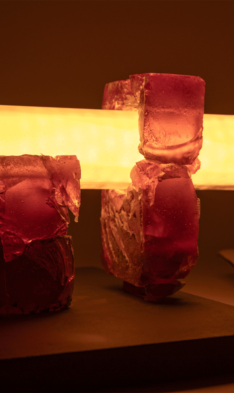 Close-up of a table lamp consisting of a thick central tube resting on two irregular amber structures
