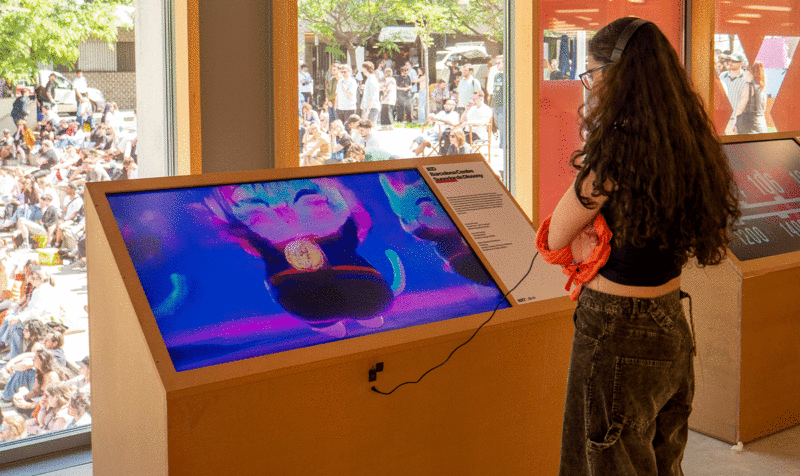 A girl watching a screen inserted in a totem that shows a short film