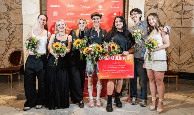 Seven students posing with bouquets of flowers at an awards ceremony photocall