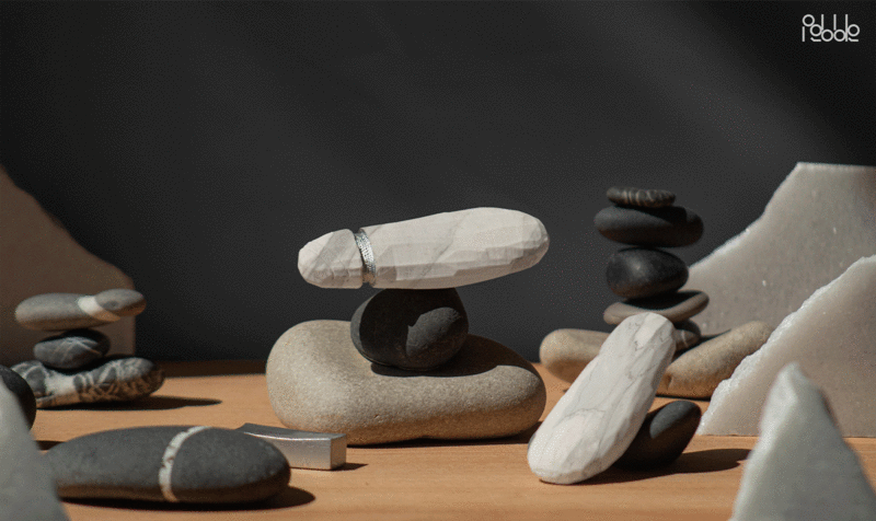 Detail shot of a table with stones arranged and a small tower in the center crowned by a stone-colored AIG device shaped like a flint point.