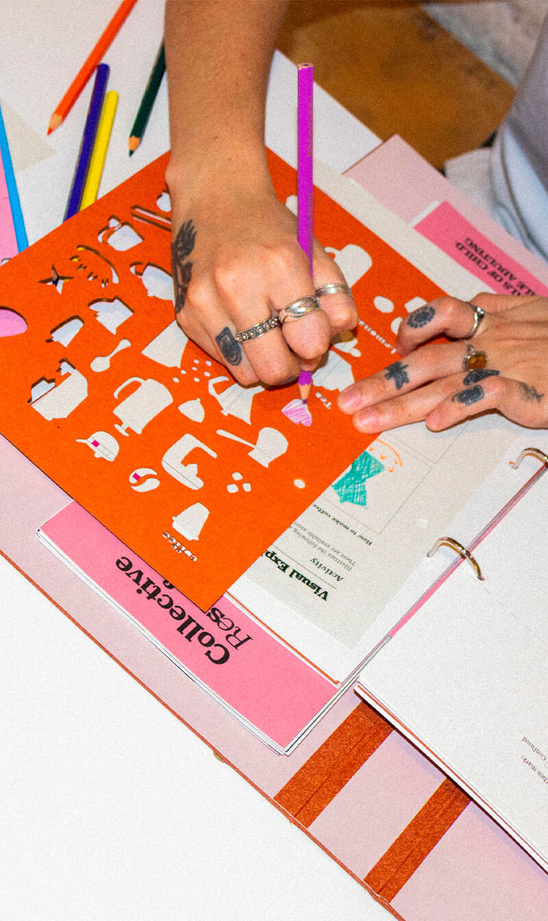 Hands drawing with a stencil on a pink activity book
