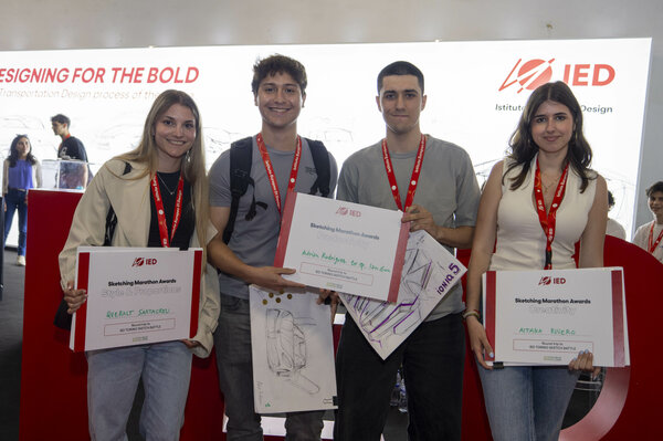 The winners, two girls and two boys, of the 3rd Sketching Marathon in front of the IED stand at the Automobile Show holding the diplomas certifying their victory