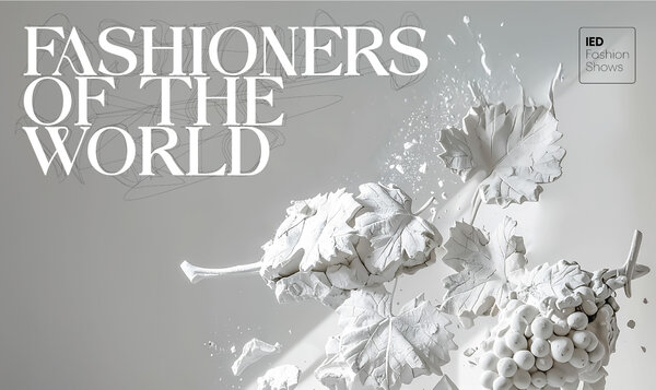 A bunch of white plaster grapes on a gray background next to the FASHIONERS OF THE WORLD fashion show lettering
