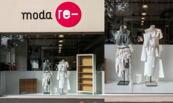 Two mannequins in front of a Moda Re-store window.
