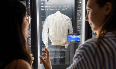 Two women admiring a white jacket displayed in a showcase in the center of the image