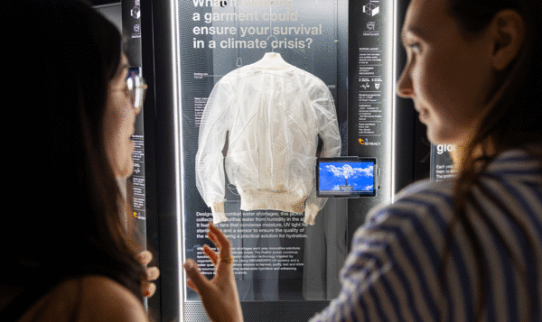 Two women admiring a white jacket displayed in a showcase in the center of the image