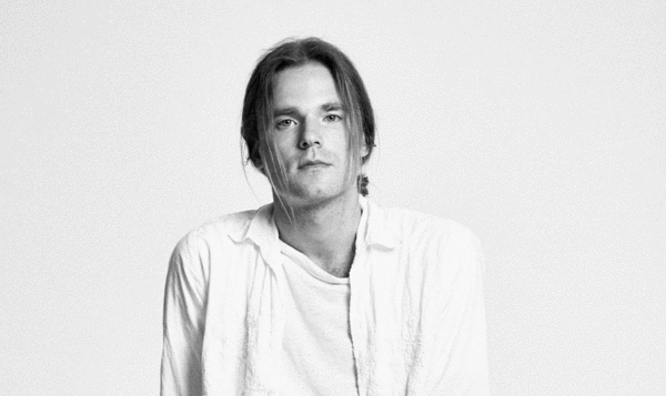 Close-up of a man in a shirt and with light hair looking at the camera. Black and white photo.