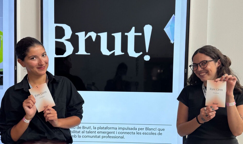 Two girls holding a paper program in front of a design festival poster