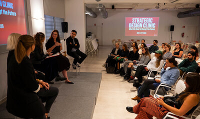 Side view of a presentation with the audience seated and five panelists