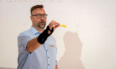 Man with glasses showing a yellow pen cap
