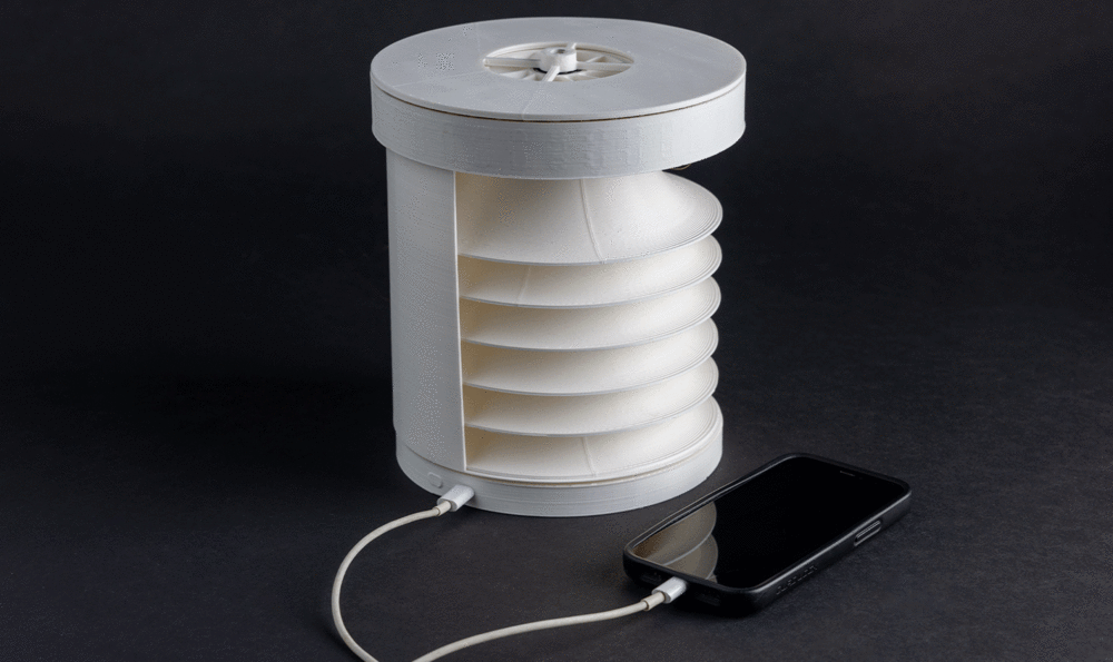 A white cylindrical device plugged into a mobile phone on a black background
