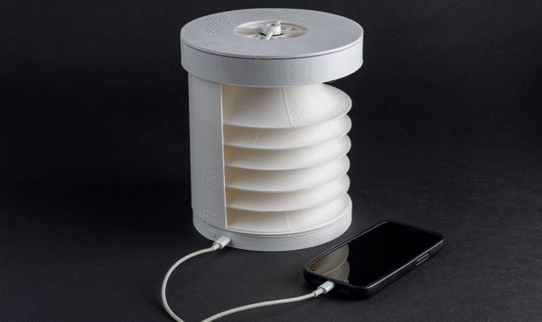 A white cylindrical device plugged into a mobile phone on a black background